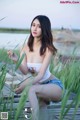 A woman sitting on a wooden boardwalk next to tall grass.