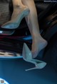 A close up of a woman's legs in high heels on a car.