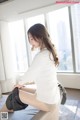 a woman sitting on top of a chair in front of a window