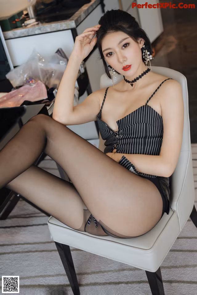 A woman sitting on a white chair wearing black stockings.