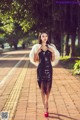 A woman in a black dress and white fur coat walking down a sidewalk.