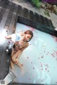 A naked woman sitting in a bathtub filled with rose petals.