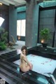 A naked woman sitting in a bathtub filled with rose petals.