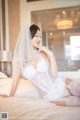 A woman in a white lingerie sitting on a bed.