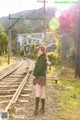 A woman in a school uniform standing on a train track.