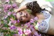 A woman laying on a rock surrounded by pink flowers.