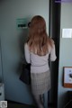 A woman standing in front of a door with her back to the camera.