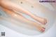 A woman's legs in a bathtub with water on them.