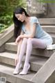 A woman sitting on the steps of a building wearing white stockings.