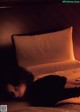 A woman laying on a bed in the dark.