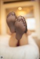 A woman laying on a bed with her feet up in the air.