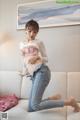 A woman in a pink bra and jeans sitting on a couch.