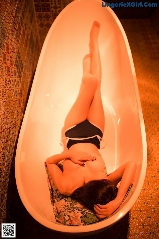 A woman laying in a bathtub in a bathroom.
