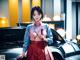 A woman in a kimono standing next to a car.