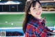 A young woman in a plaid shirt smiles at the camera.