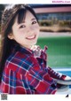 A young woman in a plaid shirt and red sneakers.