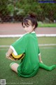 A woman sitting on the ground holding a soccer ball.