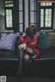 A woman sitting on a couch holding a fan.