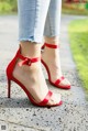 A close up of a woman wearing a pair of red heels.