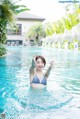 A woman in a blue bikini standing in a pool.