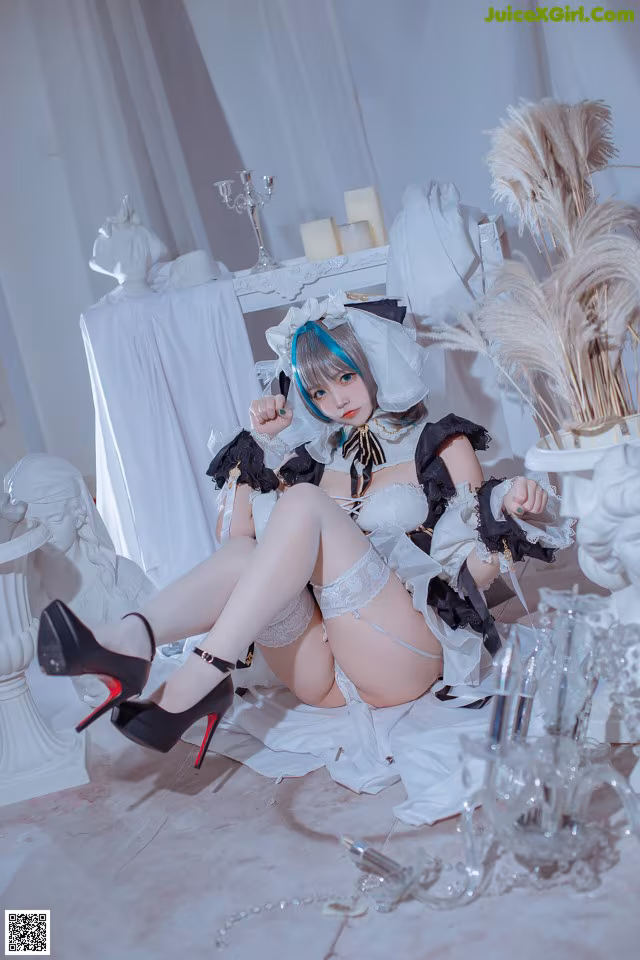 A woman in a maid outfit sitting on the floor.