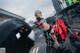 A woman in a black and red outfit standing next to a motorcycle.