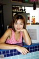 A woman in a pink polka dot tank top sitting at a bar.