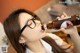 A woman wearing glasses drinking from a beer bottle.