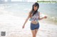 A woman standing on a beach next to the ocean.