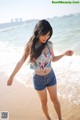 A woman standing on a beach next to the ocean.