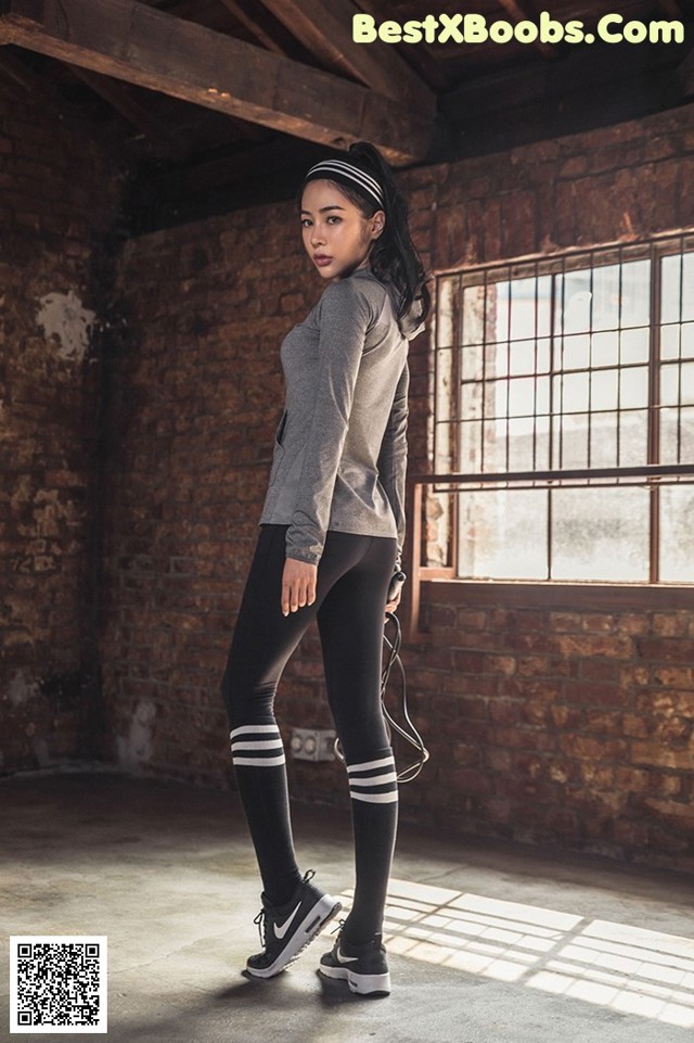 A woman standing in a room with a brick wall.