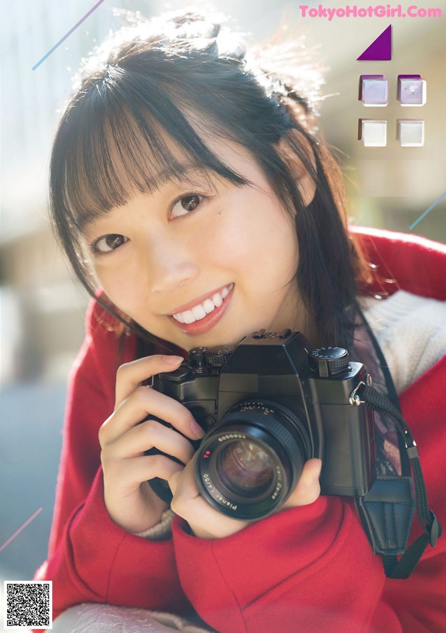 A woman holding a camera in front of her face.