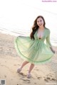 A woman in a green dress standing on a beach.