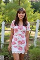 A woman standing in front of a white fence.