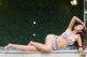 A woman in a bikini laying on the edge of a pool.