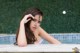 A woman in a white bikini sitting in a swimming pool.