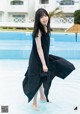 A woman in a black dress standing in a pool.