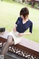 A woman sitting on a wooden bench in a park.