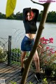 A woman standing on a wooden deck next to a body of water.