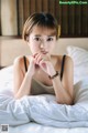 A woman laying on a bed with her hand on her chin.