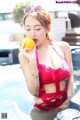 A woman in a red bikini holding an orange in a pool.